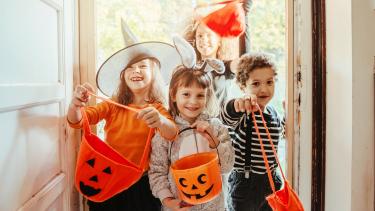 Children in Halloween costumes at the door entrance of an old house