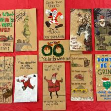 Paper bags laying flat on a red background. Bags have Christmas themed drawings on them.