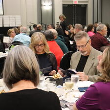 Attendees sitting at table reading the event program