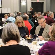 Attendees sitting at table reading the event program