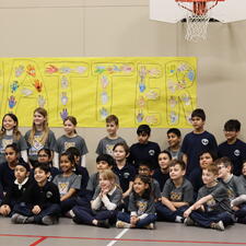 Class of students sitting and kneeling with their teacher in front of sign that reads "You Matter"