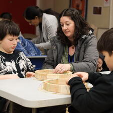 Principal sitting with students, working on making drums
