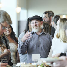 Group of people in line around a buffet table with one man in focus waiting his turn