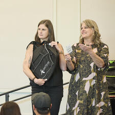 Two women standing on a stage showing off a branded bag as a prize